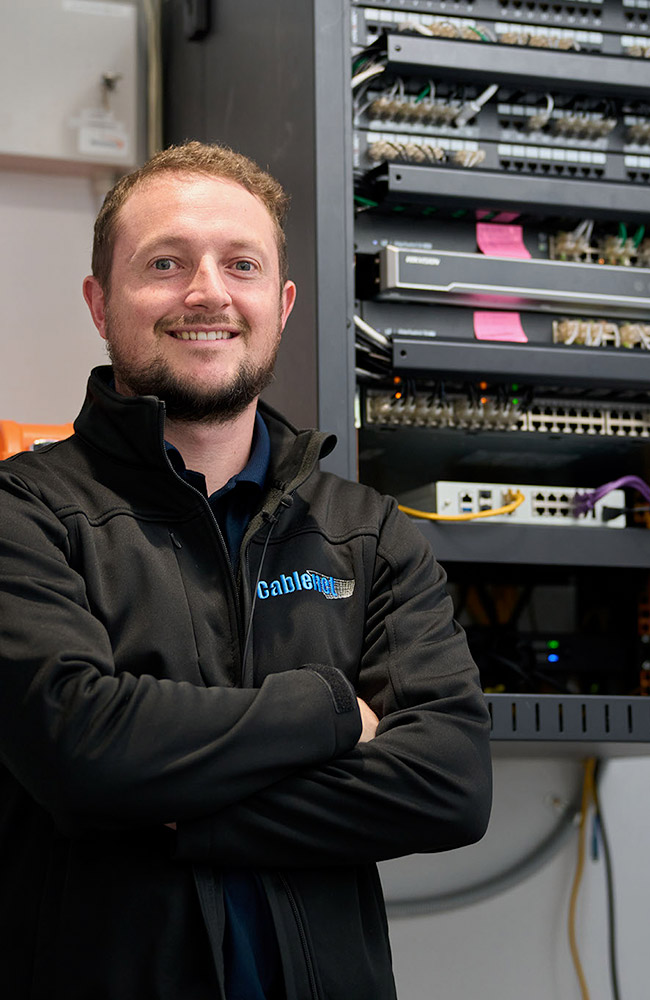 Cablenet - Team member crossing arms in front of a server console
